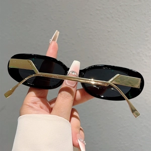 Détail de lunettes de soleil ovales avec monture noire et branche géométrique en métal doré