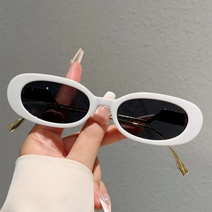 Détail de lunettes de soleil ovales blanches avec monture épaisse et branches dorées
