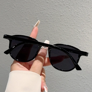 Detail of minimalist black round oversized sunglasses with thick frame and dark lenses