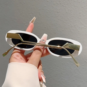 Détail de lunettes de soleil ovales blanches avec branches métalliques zigzag dorées