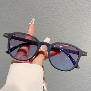 Detail of round frame sunglasses with purple gradient lenses and gold striped accents