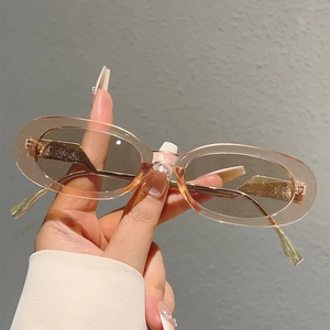 Détail de lunettes de soleil ovales en résine champagne avec branches dorées