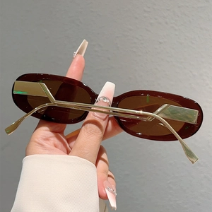 Détail des lunettes de soleil ovales avec monture en métal doré et branches stylisées
