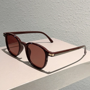 Detail of dark burgundy round frame sunglasses with elegant gold metal hinge accents