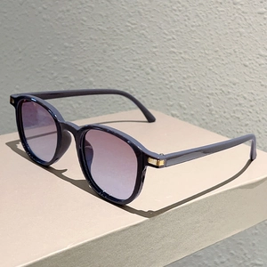 Detail of dark purple sunglasses with gradient lenses and gold metallic hinge accents