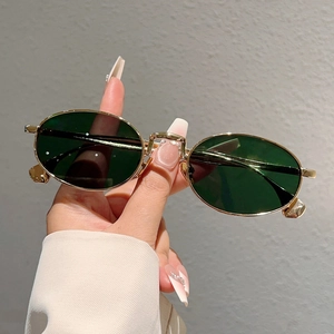 Dettaglio degli occhiali da sole ovali vintage con lenti verde scuro e montatura in metallo dorato