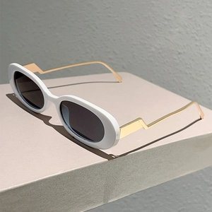 Lunettes de soleil ovales blanches avec branches dorées en éclair sur socle gris