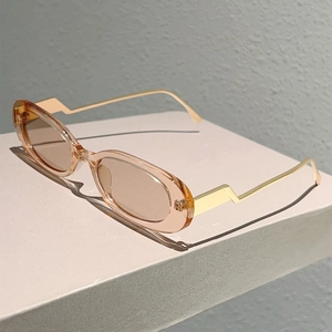 Gros plan de lunettes de soleil ovales ambrées avec branches dorées en zigzag