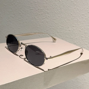 Dettaglio degli occhiali da sole ovali vintage con montatura in metallo argento e lenti scure