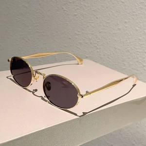 Dettaglio occhiali da sole ovali vintage con montatura in metallo oro e lenti fumo