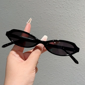 Détail de lunettes de soleil ovales noires rétro avec monture fine en plastique à la main