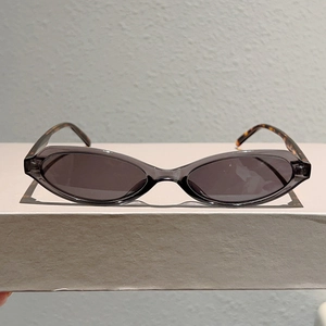 Détail de lunettes de soleil œil-de-chat grises avec monture translucide et branches écaillées