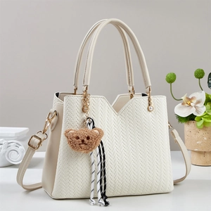 Elegante borsa tote intrecciata crema con ciondolo a forma di orso e tracolla regolabile