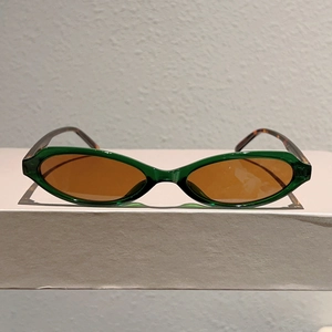 Détail de lunettes de soleil yeux de chat avec monture verte et branches en écaille