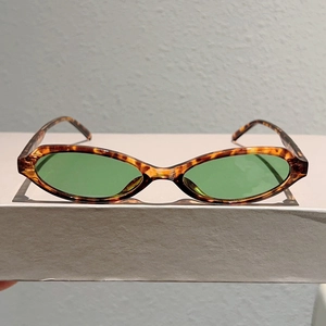 Détail des lunettes de soleil vintage œil-de-chat en écaille avec verres verts