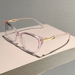 Detail of pink transparent cat-eye frame with gold metal temples and oval hollow accents