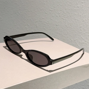 Vue détaillée de lunettes de soleil ovales noires rétro avec finition brillante sur socle