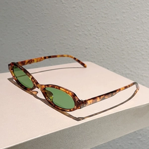 Gros plan de lunettes de soleil ovales en écaille rétro avec verres verts et charnières en métal