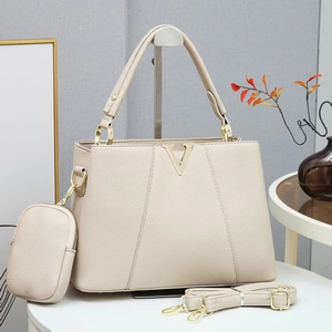 Detail of beige lychee grain leather handbag with gold V buckle and mini charm bag