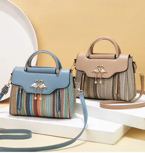 Detail of colorful woven shoulder bag with gold swan clasp and elegant metal top handle