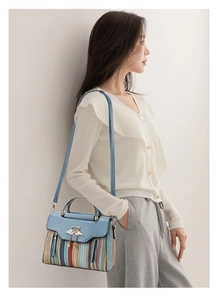 Blue leather and woven handbag with swan hardware worn by a model in a minimal setting
