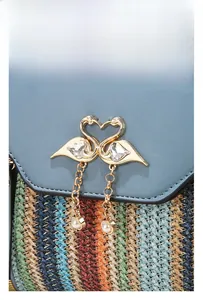 Detail of blue leather flap and woven stripe texture with a gold swan clasp and pearls