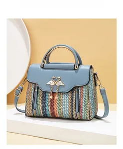 Close-up of the woven striped bag featuring a heart-shaped buckle and pearl tassels