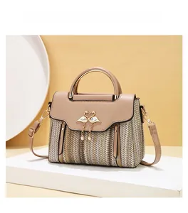 Detail of woven texture handbag with golden flamingo buckle and pearl pendant