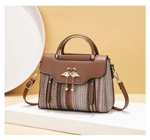 Close-up of woven crossbody bag with golden swan hardware and metallic top handle