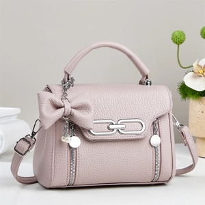 Detail der altrosa Lederhandtasche mit Schleife, Perlenanhänger und Silberbeschlägen