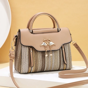 Fashionable woven tote bag for women with gold swan clasp and pearl tassels on display