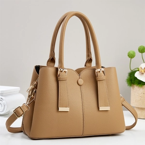 Detail of tan pebble leather handbag with gold hardware and removable shoulder strap