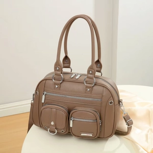 Detailed view of brown lychee leather messenger bag with silver zippers and metal rings