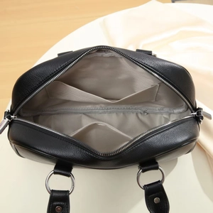 Interior view of black pebbled leather messenger bag with grey herringbone fabric lining