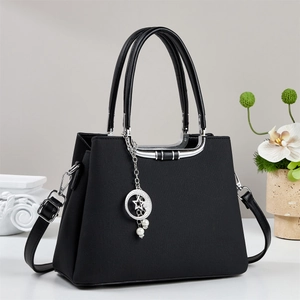 Detail of black crossbody bag with silver U-shaped metal trim and pearl star pendant