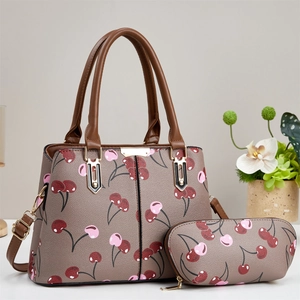 Detail der kaffeebraunen Handtasche mit Kirschmuster und passendem kleinen Beutel