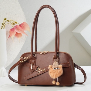 Sac à main demi-lune marron foncé en simili cuir avec pendentif peluche sur fond blanc