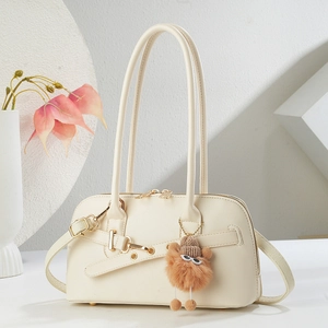 Détail du sac cabas en cuir crème avec boucles dorées et breloque en peluche marron