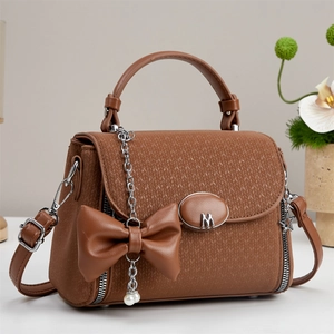 Brown cross-body bag with woven texture, large leather bow, and pearl chain strap decoration