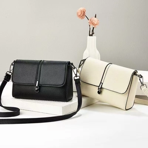 Detail of soft lychee leather crossbody bags in black and beige with metal ball clasp