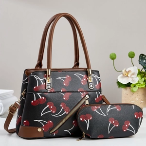 Detail of cherry print handbag set with brown handles on a white marble surface