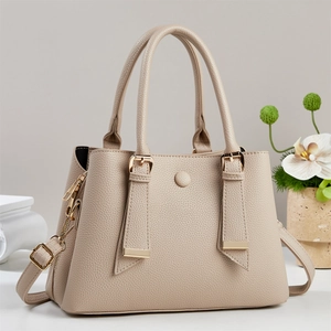 Detail der beigen Handtasche aus Leder mit Lychee-Narben und goldfarbenen Elementen