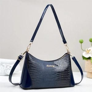 Classic dark blue crocodile embossed leather handbag with gold hardware on white pedestal
