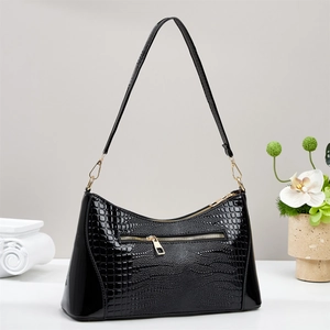 Close-up of black crocodile pattern leather handbag featuring premium gold metal hardware