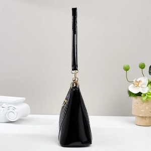 Detail of glossy black crocodile embossed leather handbag with premium gold hardware