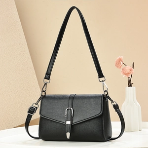 Elegant black pebble leather crossbody bag with silver horseshoe buckle on beige background