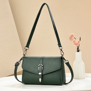 Elegant dark green leather crossbody bag with silver horseshoe buckle in minimalist home setting