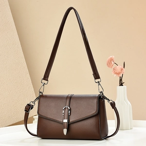 Detailed view of brown litchi grain PU leather bag with silver buckle on beige background
