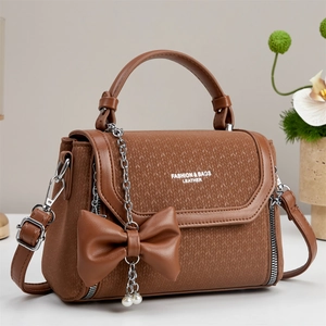Brown leather crossbody bag with textured panel, bow pendant and pearl chain detail