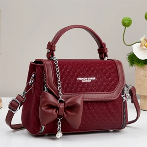Detailed close-up of burgundy leather crossbody bag with bow pendant and star chain